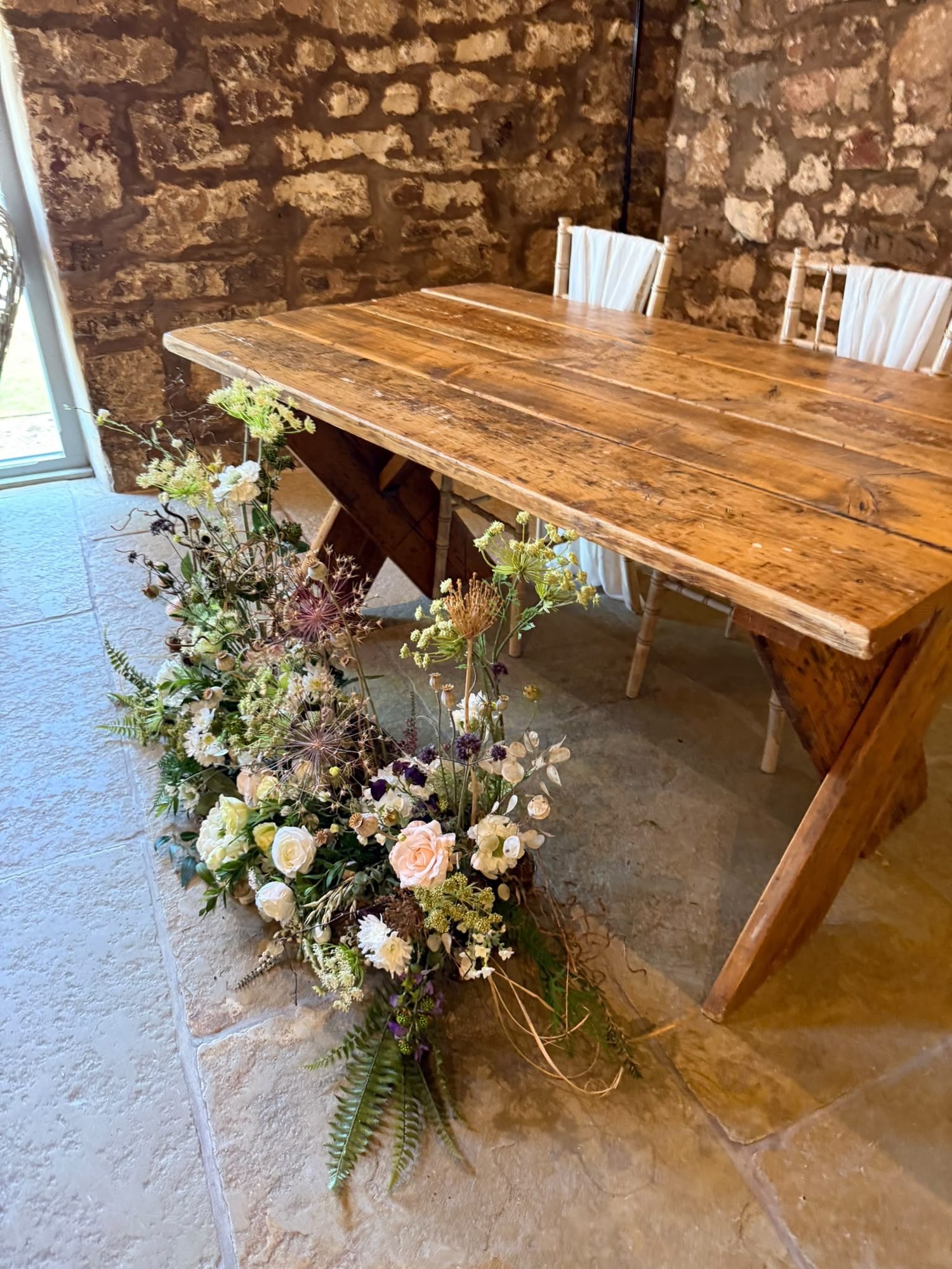 Long wooden table with a cascading floral arrangement to the floor